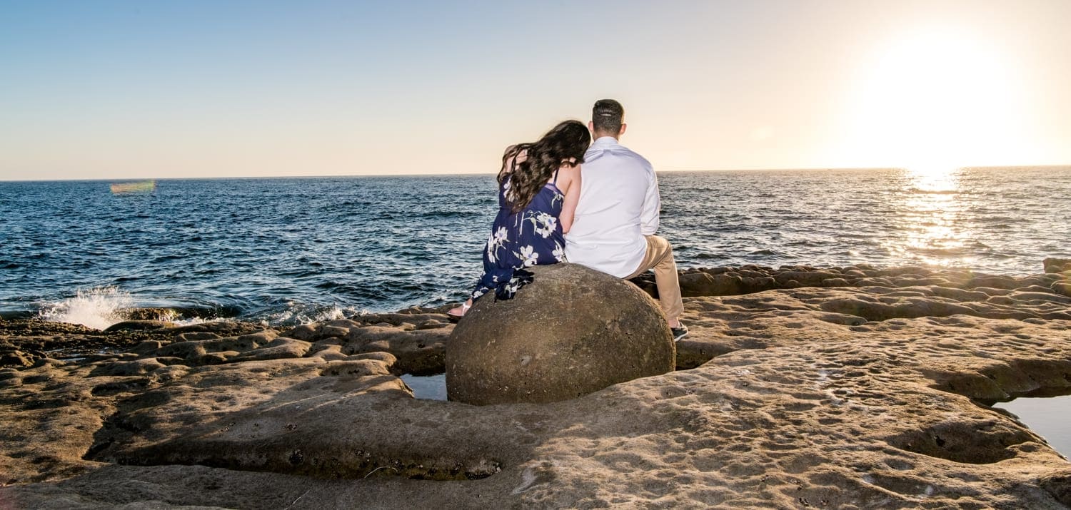 Couple sitting on a rock watching the sunset.