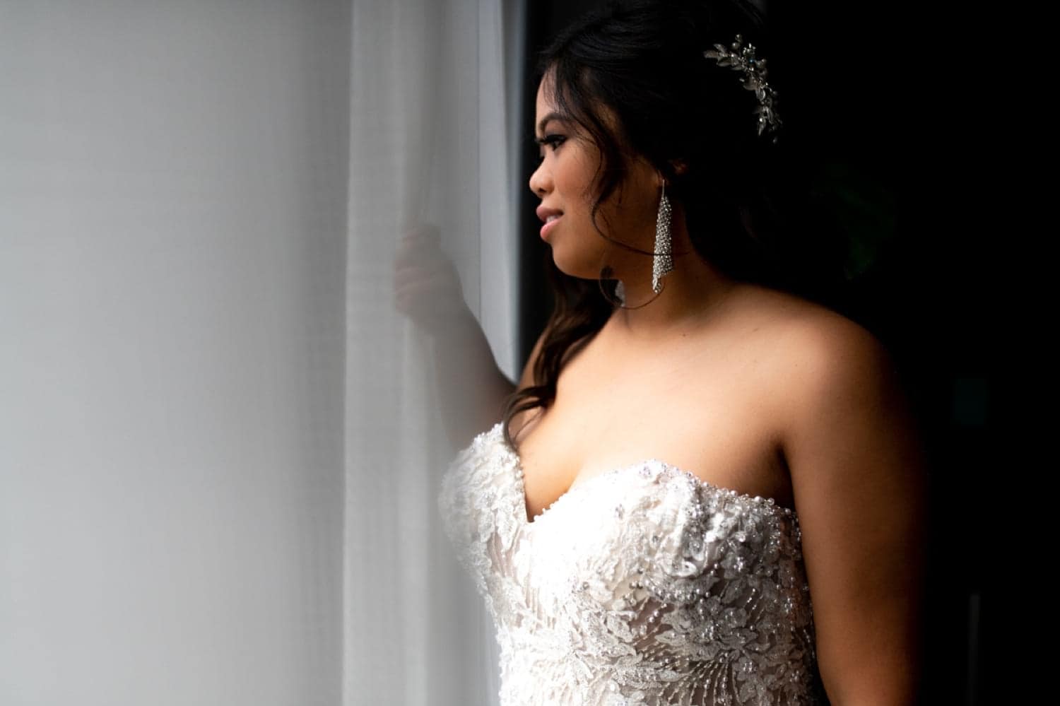 Bride looking out the window of her hotel room. 