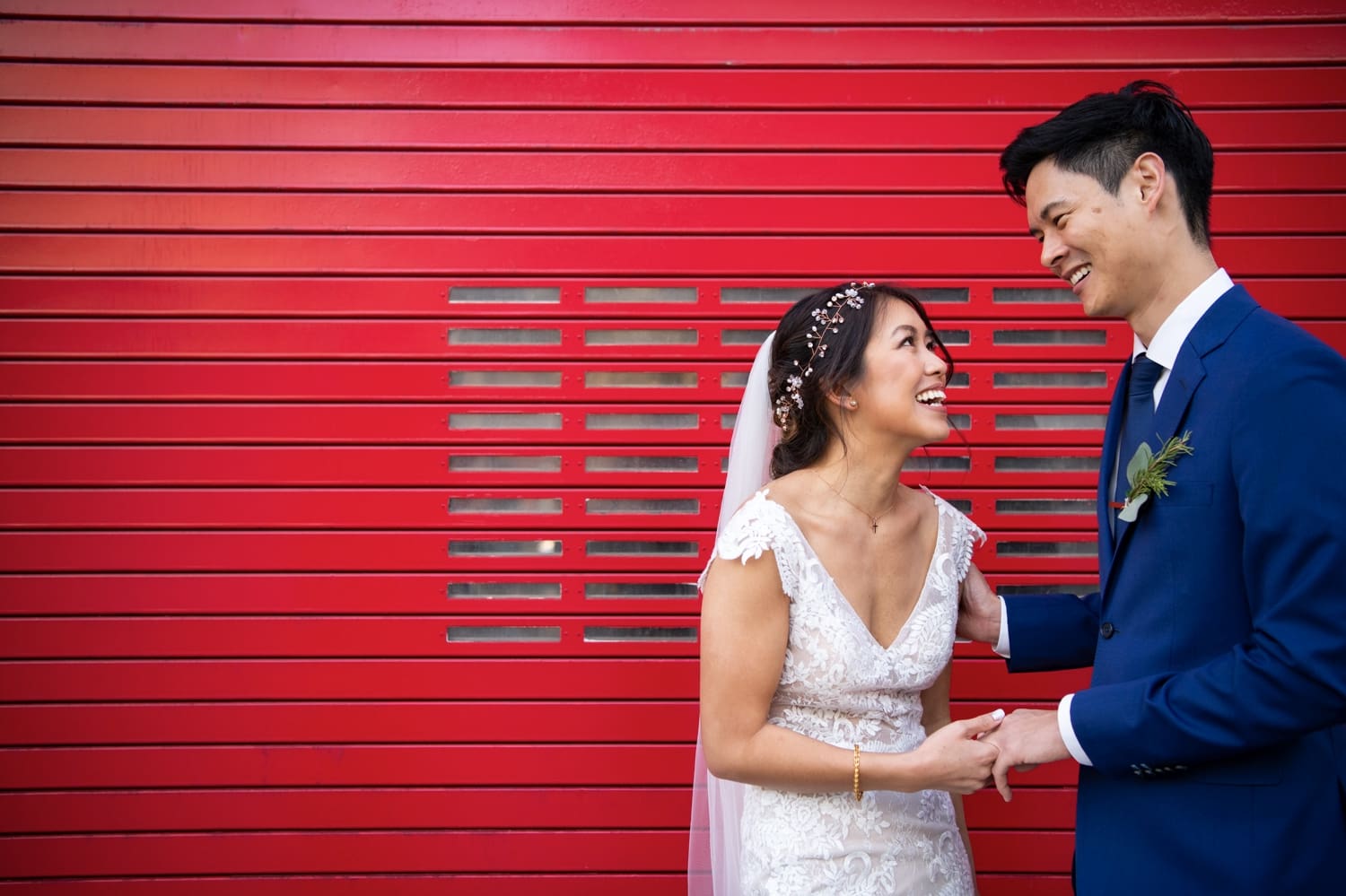 Bride and groom in front of big red door. 