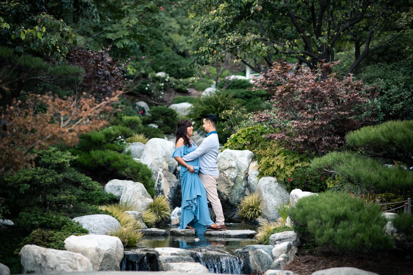 Couple holding one another in front of waterfall at Japanese Friendship Garden in Balboa Park.